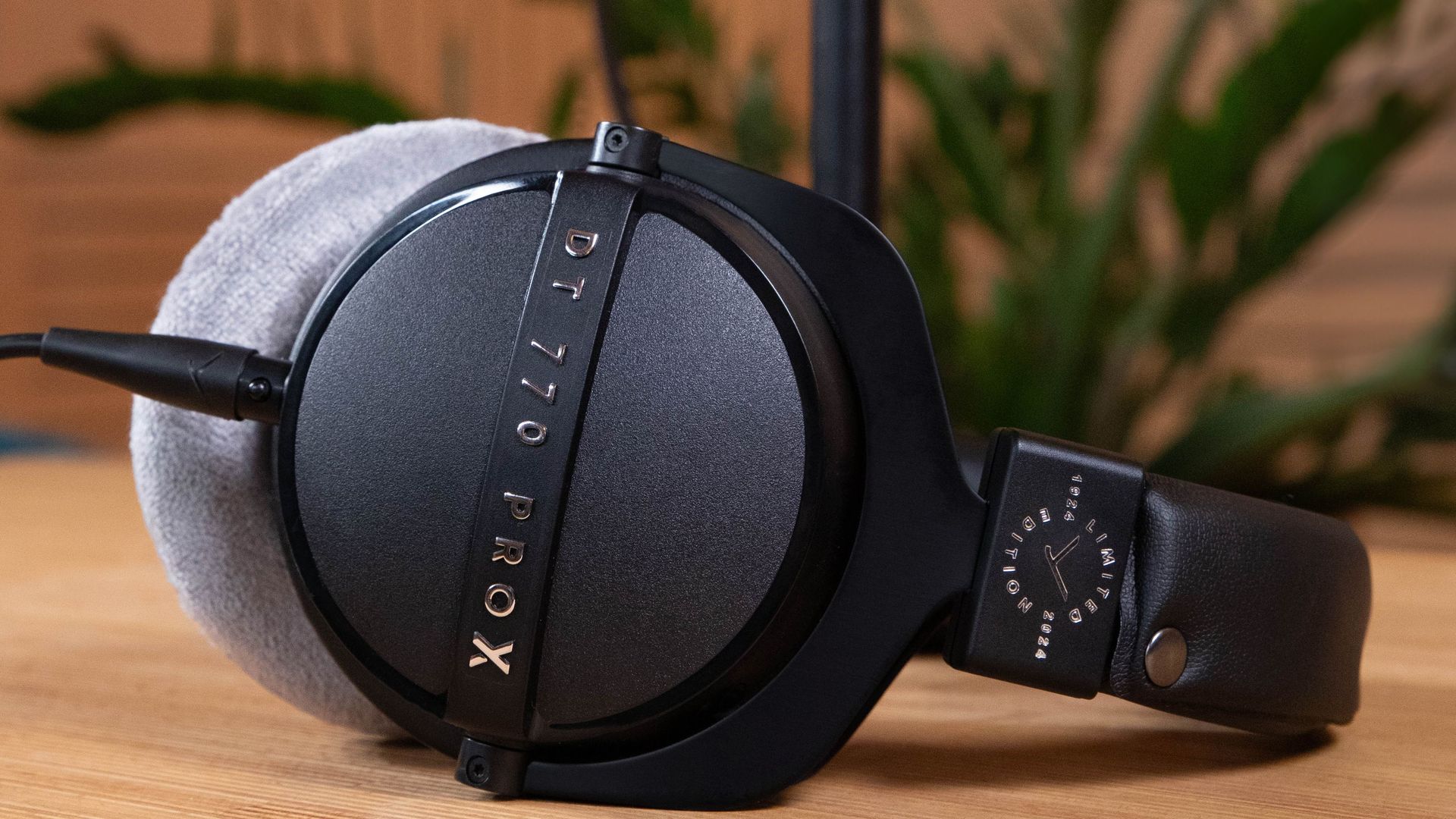 The Beyerdynamic DT 770 Pro is shown in a side profile with a black finish, resting on a wooden surface.