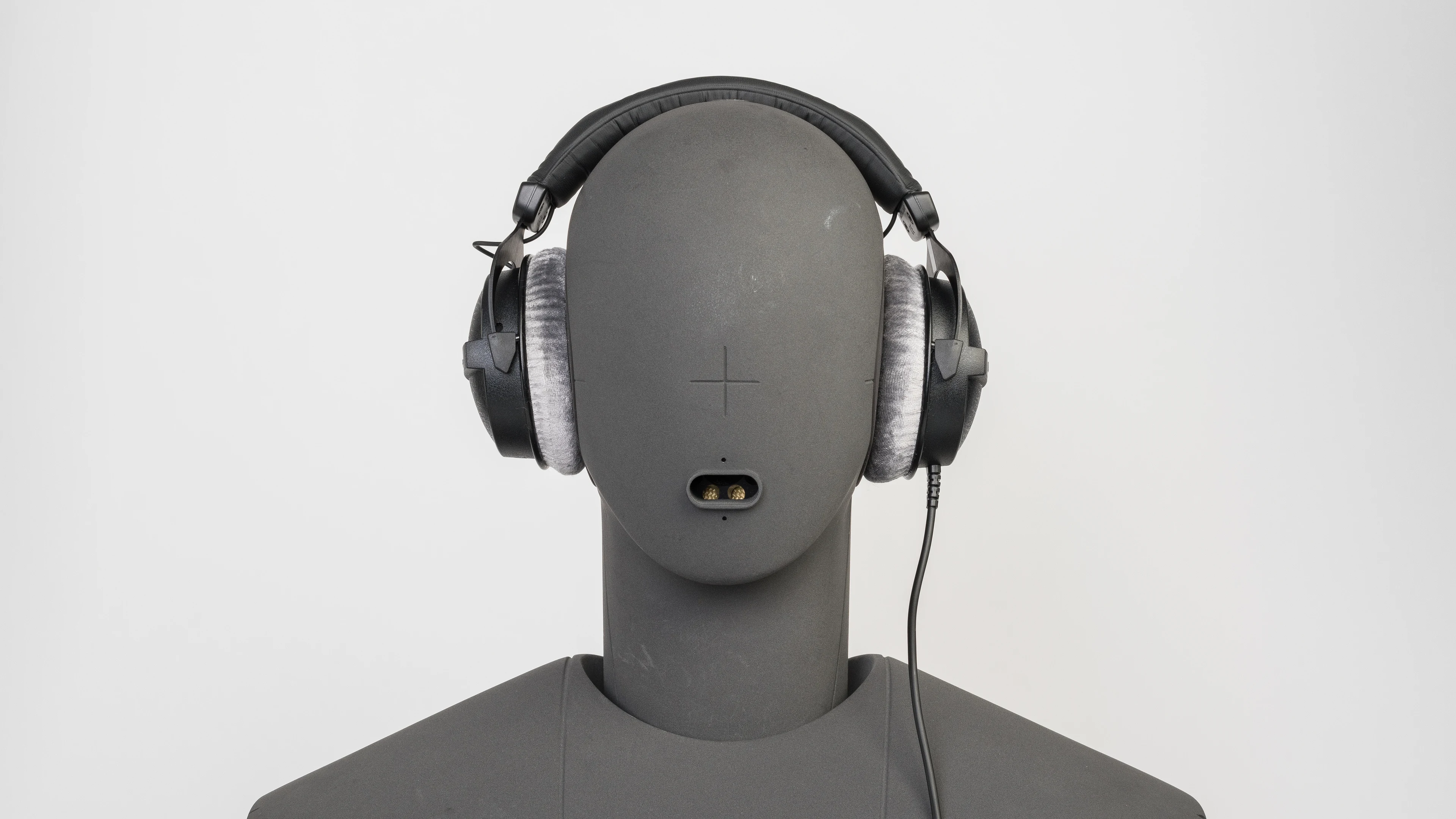 A mannequin head with a pair of over-ear headphones on, viewed from the front.