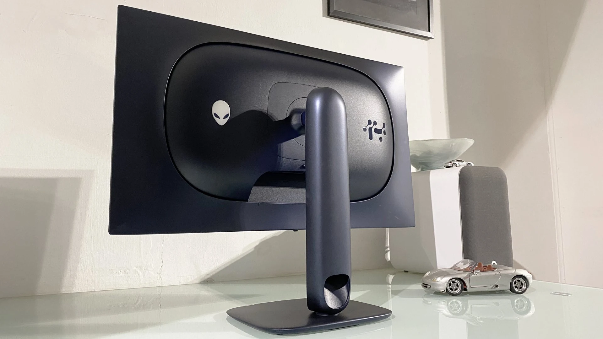 The Dell Alienware AW2725Q monitor is shown in a side profile, resting on a sleek stand with the Alienware logo visible on its back.