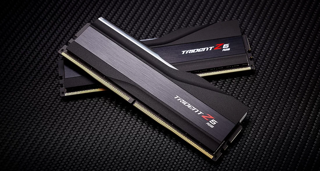 Two black Trident Z5 RGB memory modules are shown from a three-quarter angle, resting on a textured dark background.