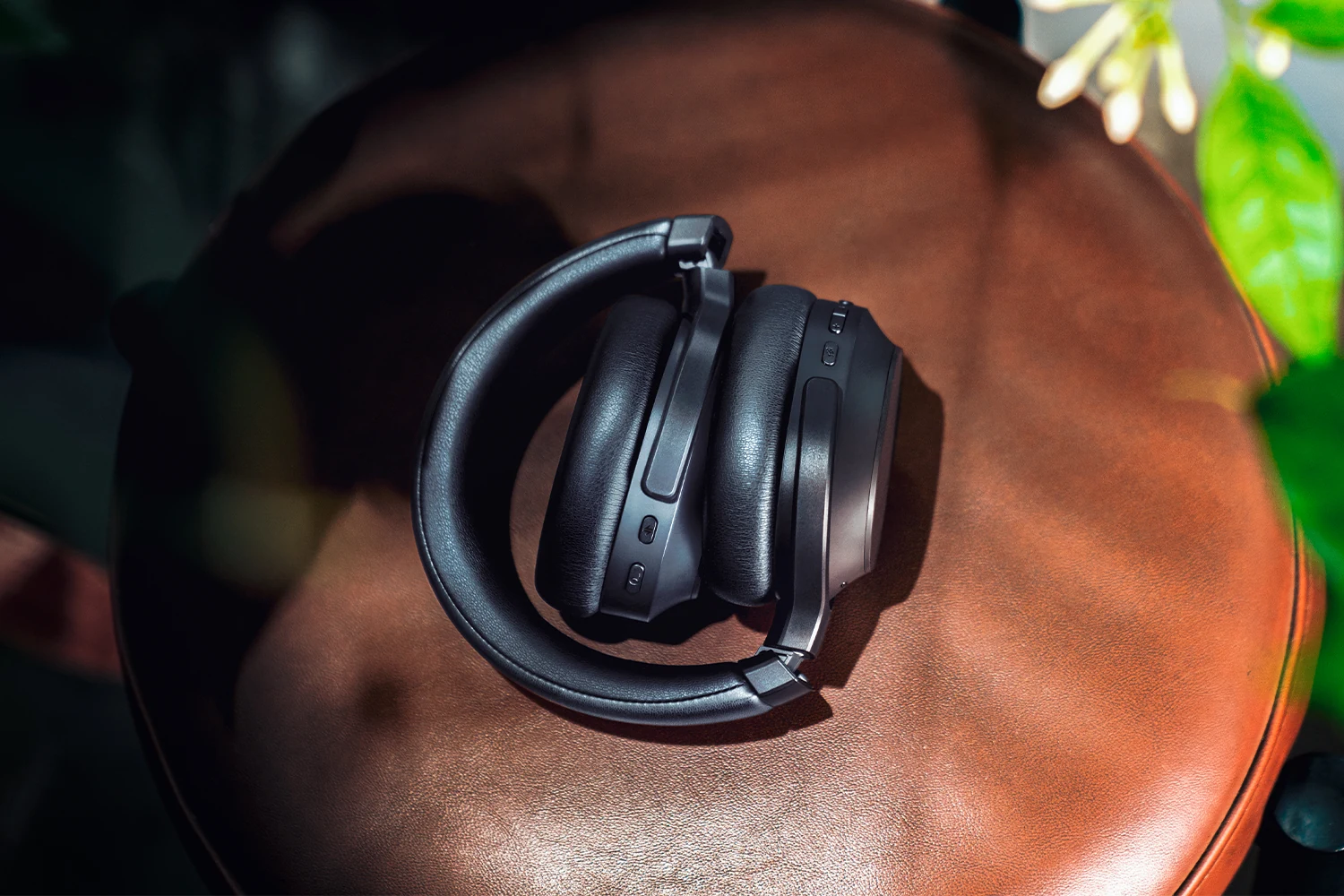 The Razer Barracuda V2 Pro headset is shown from a top-down angle, resting on a brown leather surface with some greenery in the background.