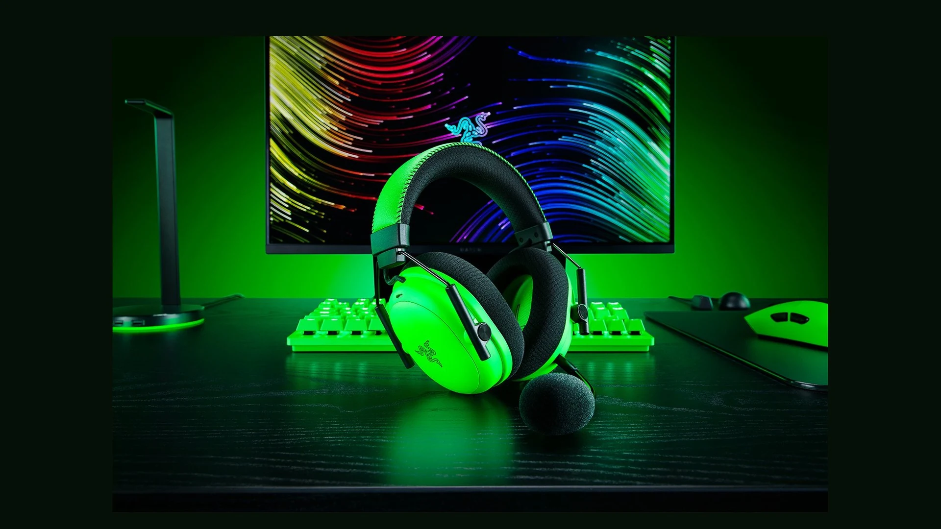 A bright green Razer BlackShark V3 Pro Esports Green Edition headset is shown in a three-quarter angle on a desk with matching peripherals.