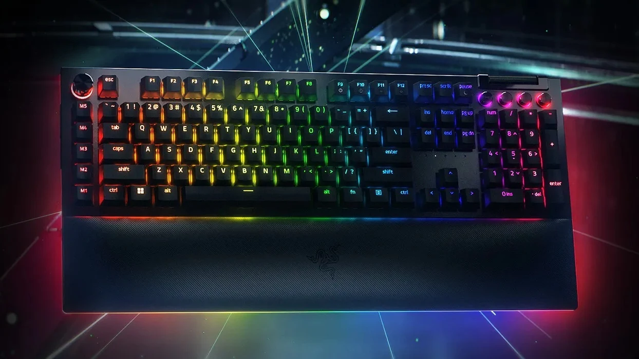 The Razer BlackWidow V4 Pro full-size keyboard with per-key RGB lighting, the Command Dial at top left, media keys and roller at top right, and its magnetic wrist rest attached.