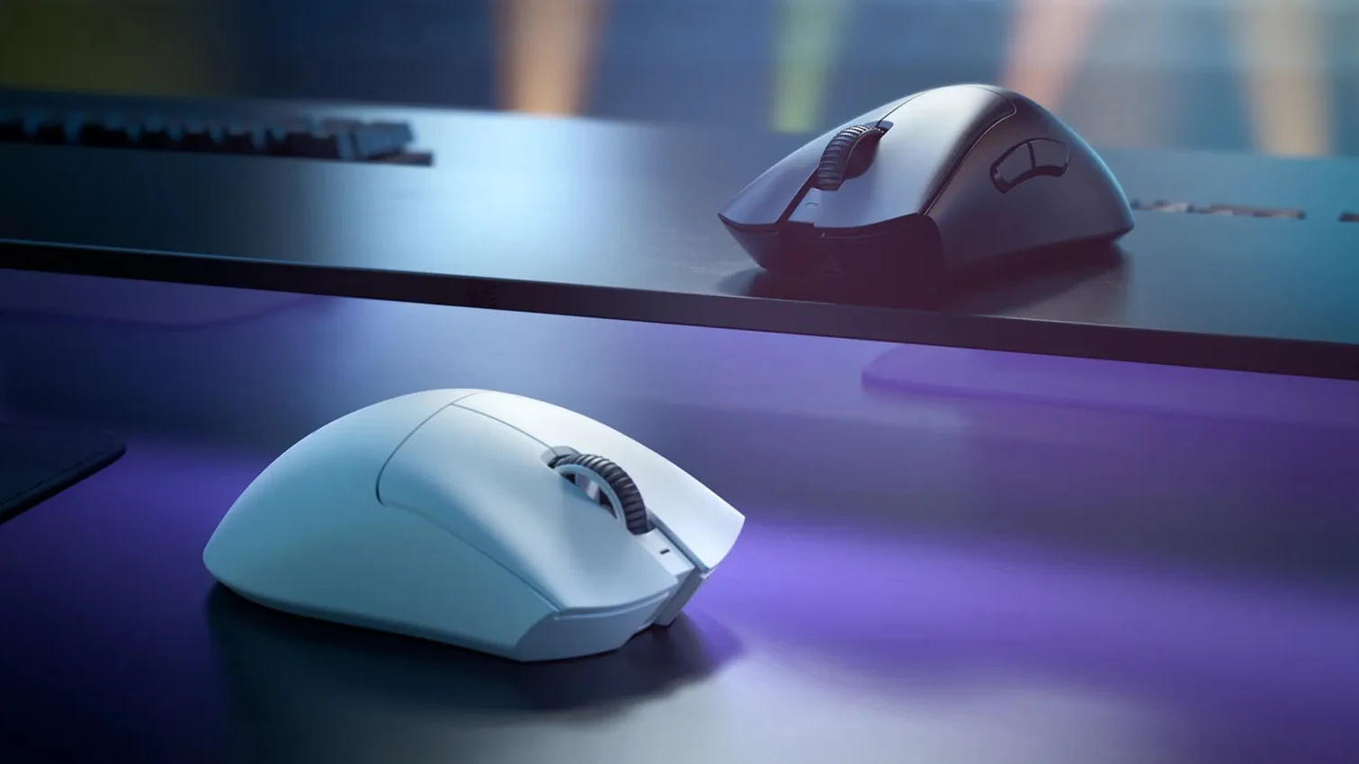 A white Razer DeathAdder V3 Pro on a desk in the foreground with the black version behind it, lit in purple and blue.