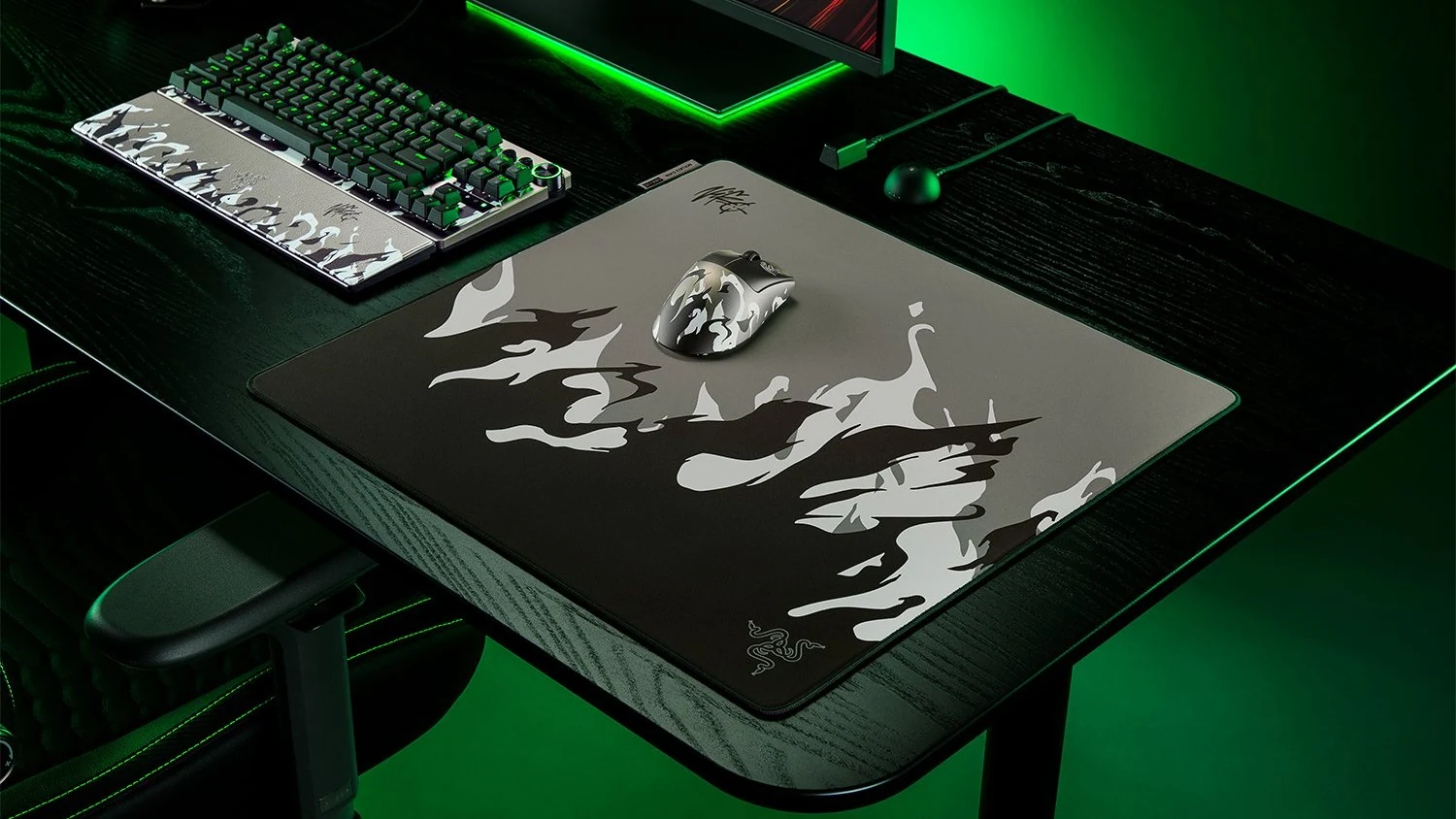 The Razer Gigantus V2 Pro Large NiKo Edition mousepad is shown in a top-down view, featuring a camouflage design and placed on a desk with other gaming peripherals.