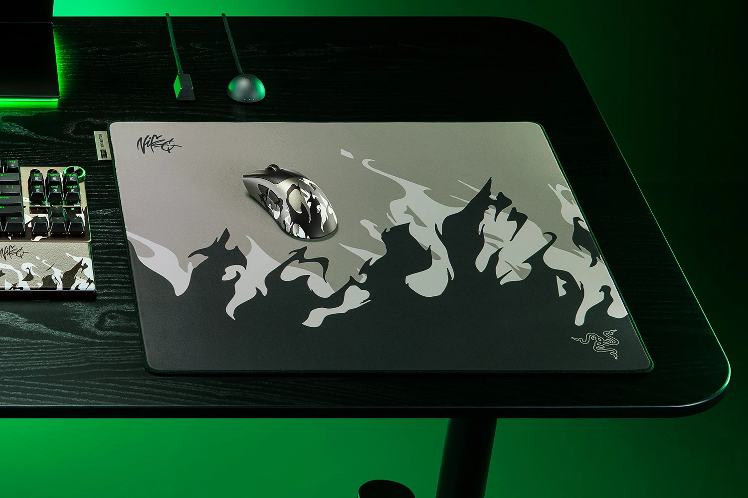 The Razer Gigantus V2 Pro Large NiKo Edition mousepad is shown in a top-down view with a camouflage-patterned mouse placed on it, set against a dark wooden desk.