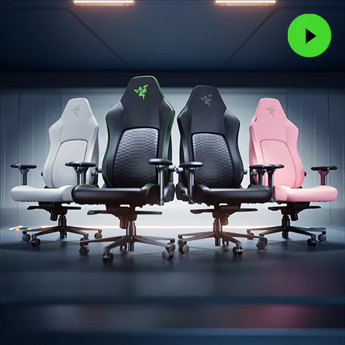 Four Razer Iskur V2 NewGen gaming chairs in white, black with green accents, black with gray accents, and pink are displayed side by side on a dark floor against a wooden wall.