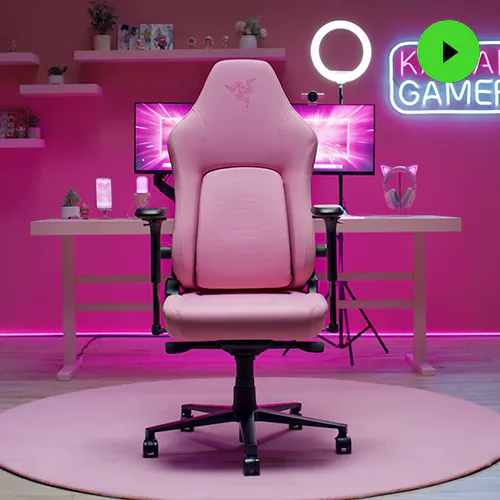 The Razer Iskur V2 NewGen gaming chair is shown in a three-quarter view, featuring its pink upholstery and ergonomic design with visible armrests and wheels.