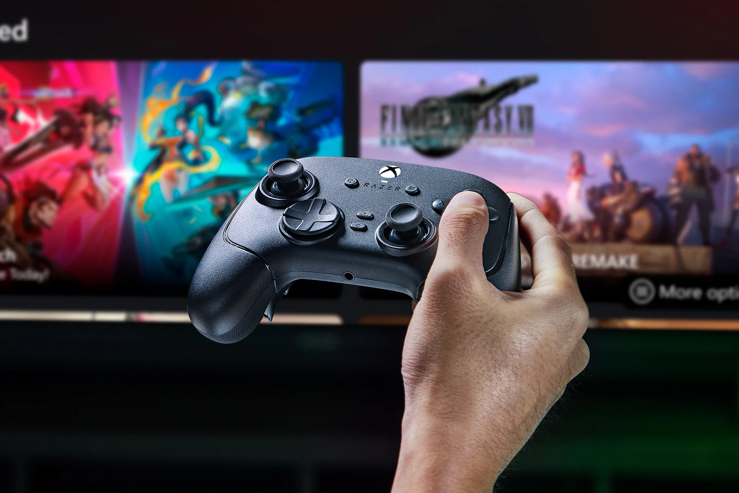 A hand holding a black Razer controller in front of a TV screen displaying game graphics.