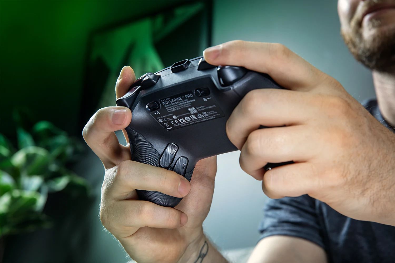 A close-up of a person holding the Razer Wolverine V4 Pro controller, focusing on its back panel with visible text and buttons.
