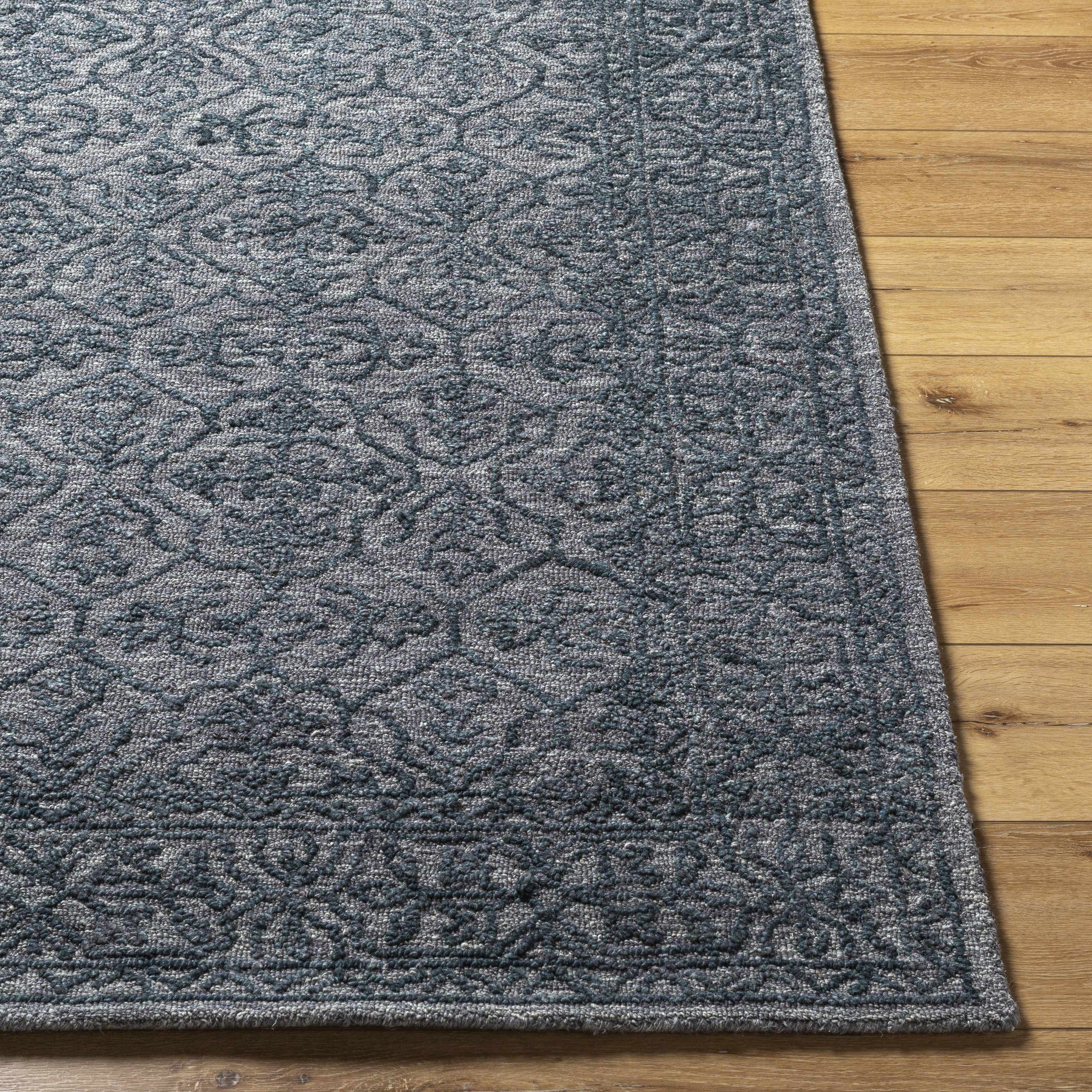 The rug has a dark blue and gray pattern with intricate designs, placed on a wooden floor.