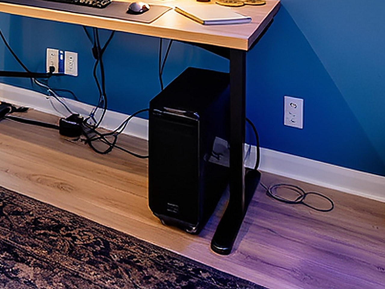 Close-up of the black rectangular desktop case showing blue glowing fans and internal hardware.
