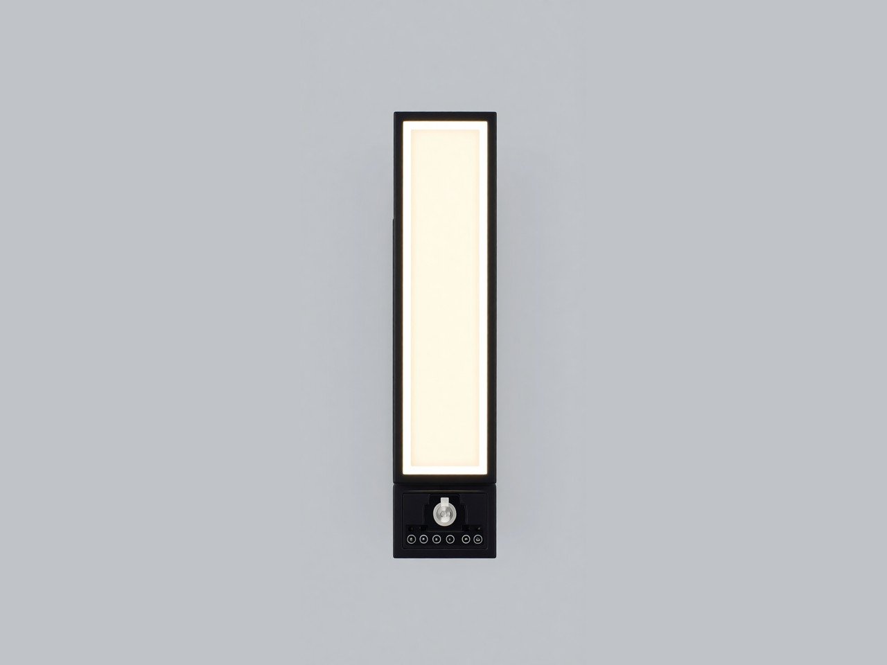 A black rectangular wall sconce with a tall warm-white light panel, shown on a plain grey background.