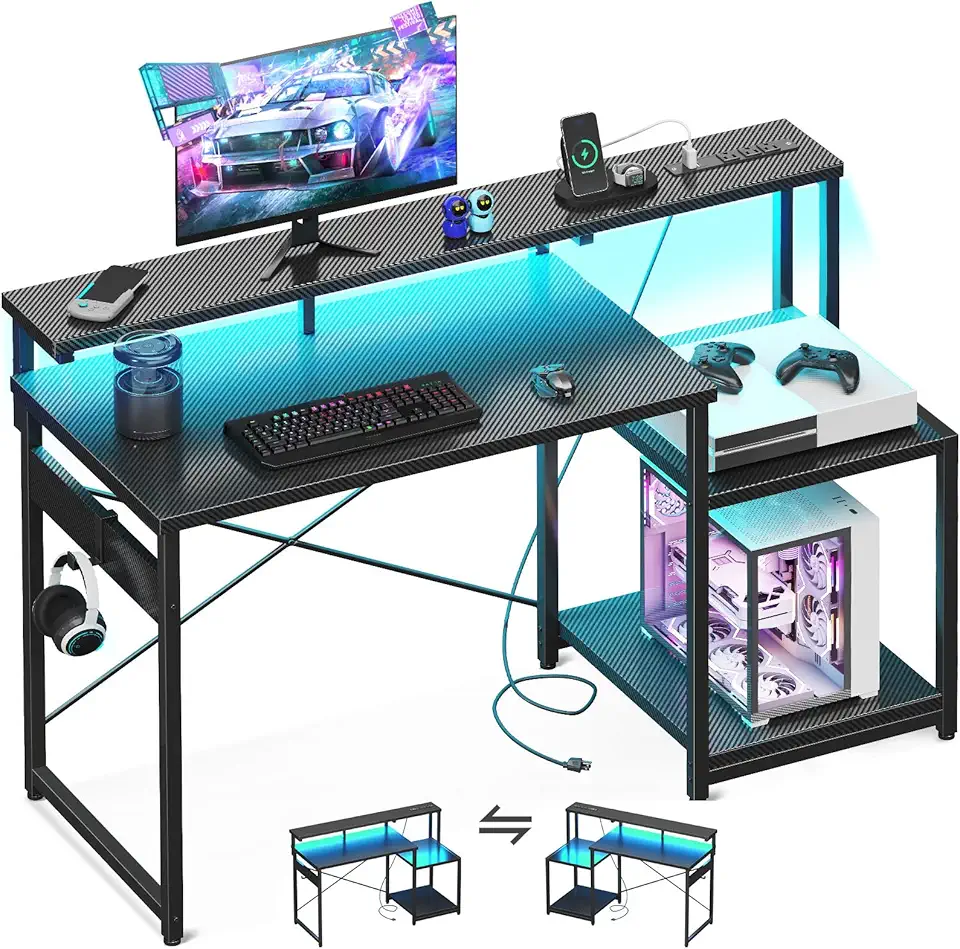 The image shows a black gaming desk with blue LED lighting, featuring two shelves and a CPU stand underneath. The desk has various accessories like a monitor, keyboard, mouse, headphones, and controllers placed on it.