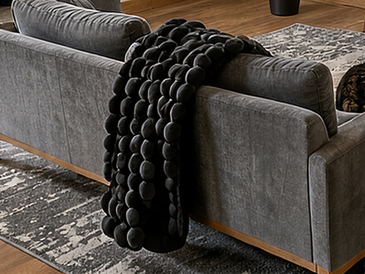 A close-up of the black fluffy faux fur throw blanket on the sofa.