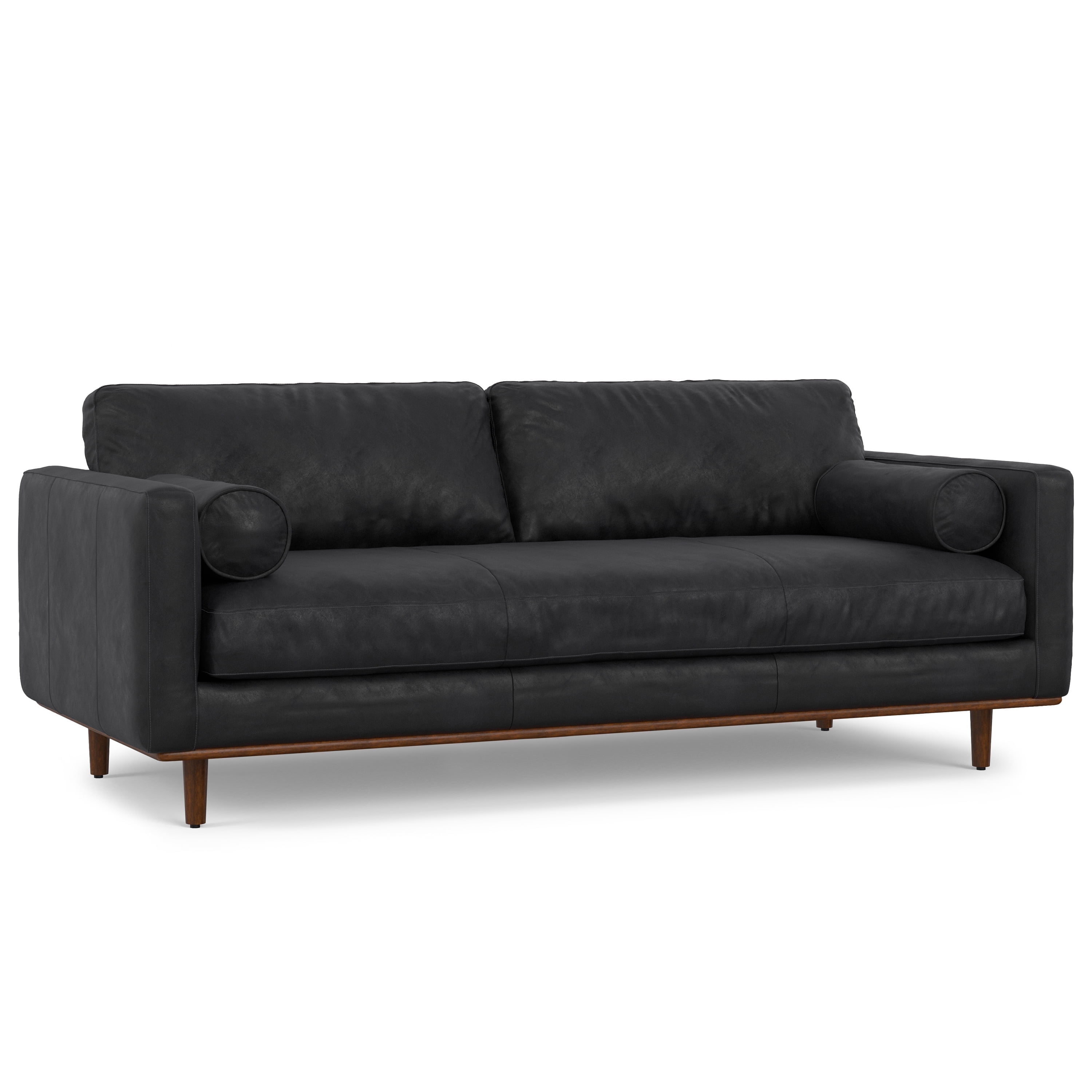 A black leather sofa with wooden legs and circular armrests, photographed from a side profile.