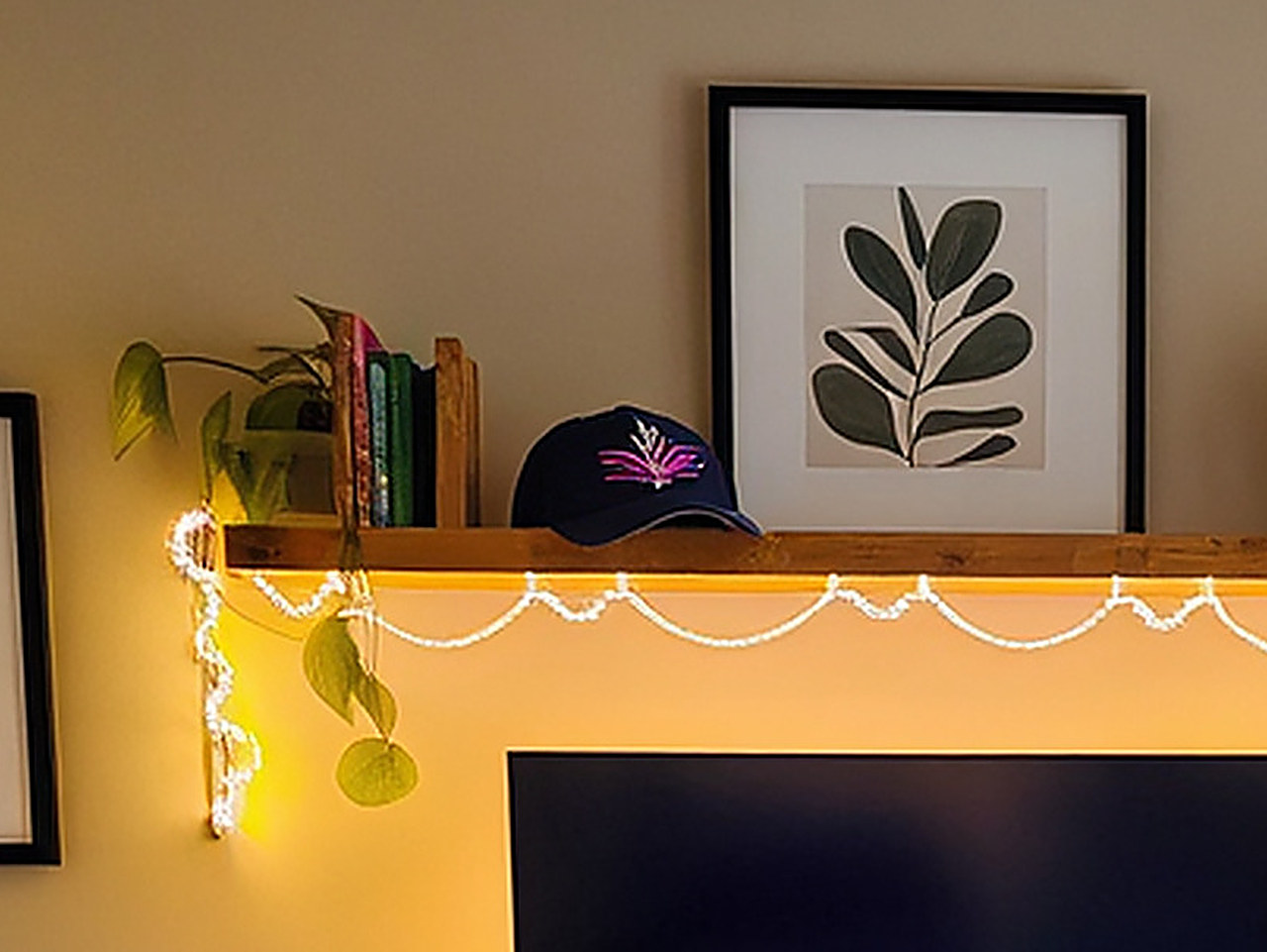 Close-up of a navy blue baseball cap with pink and white embroidery resting on a wooden shelf.