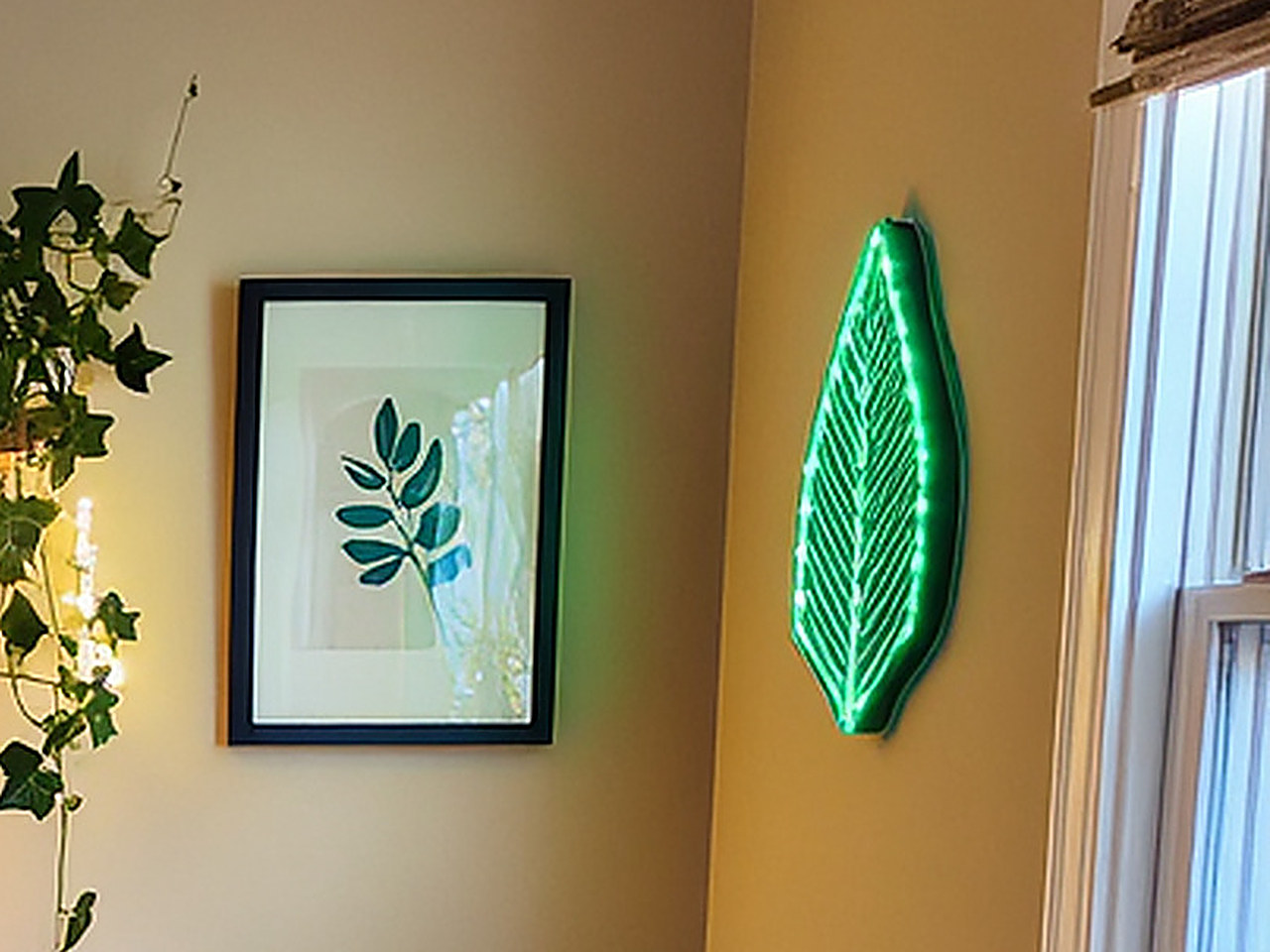 Close-up of a glowing green LED leaf-shaped wall sign mounted on a warm beige wall.