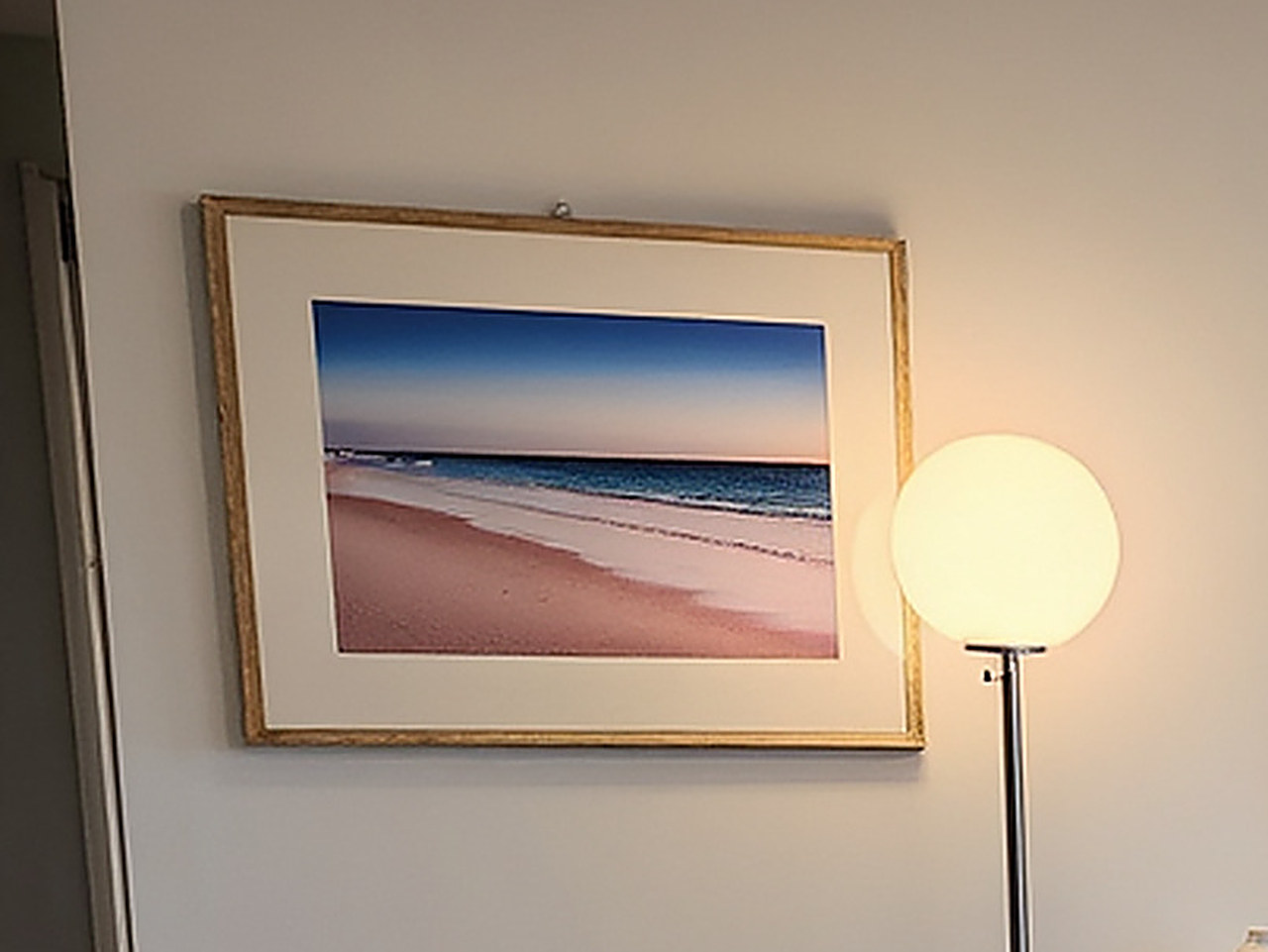Close-up of the framed canvas print showing a tranquil beach scene with pink sand and blue sky.