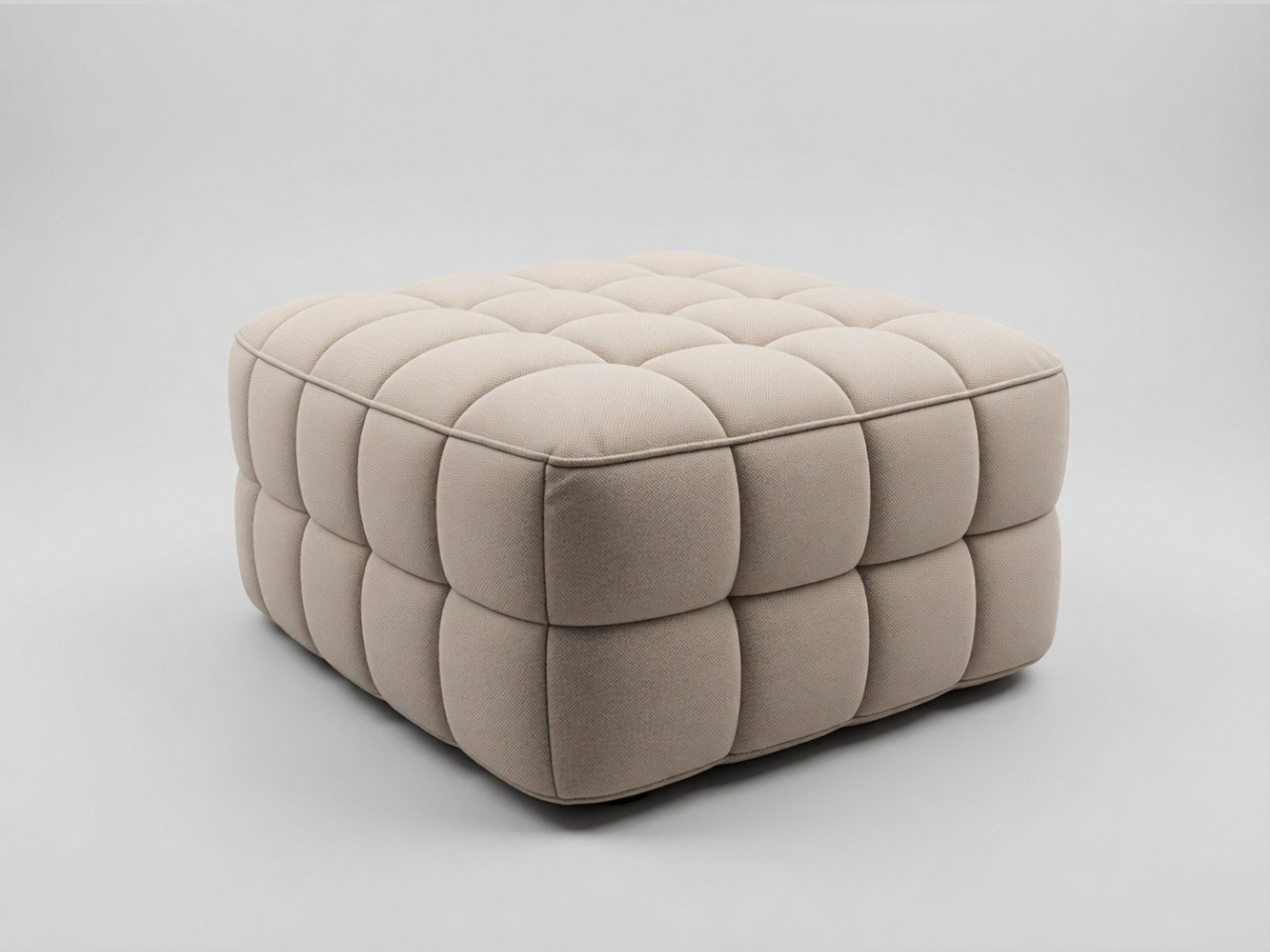 A beige, square, tufted ottoman with a quilted design made of fabric, placed on a plain grey background.