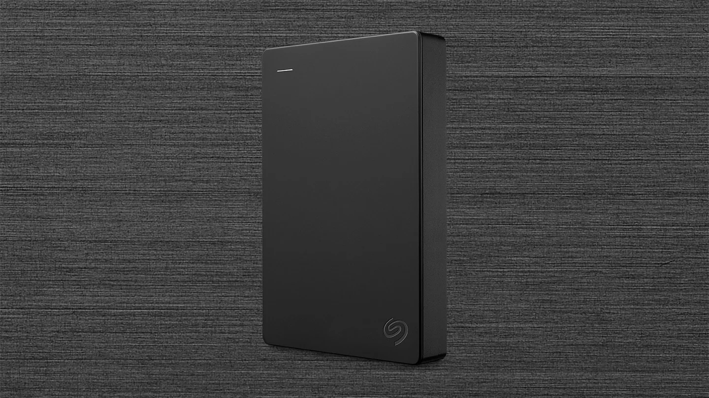 A black Seagate portable hard drive is shown in a side profile against a textured background.