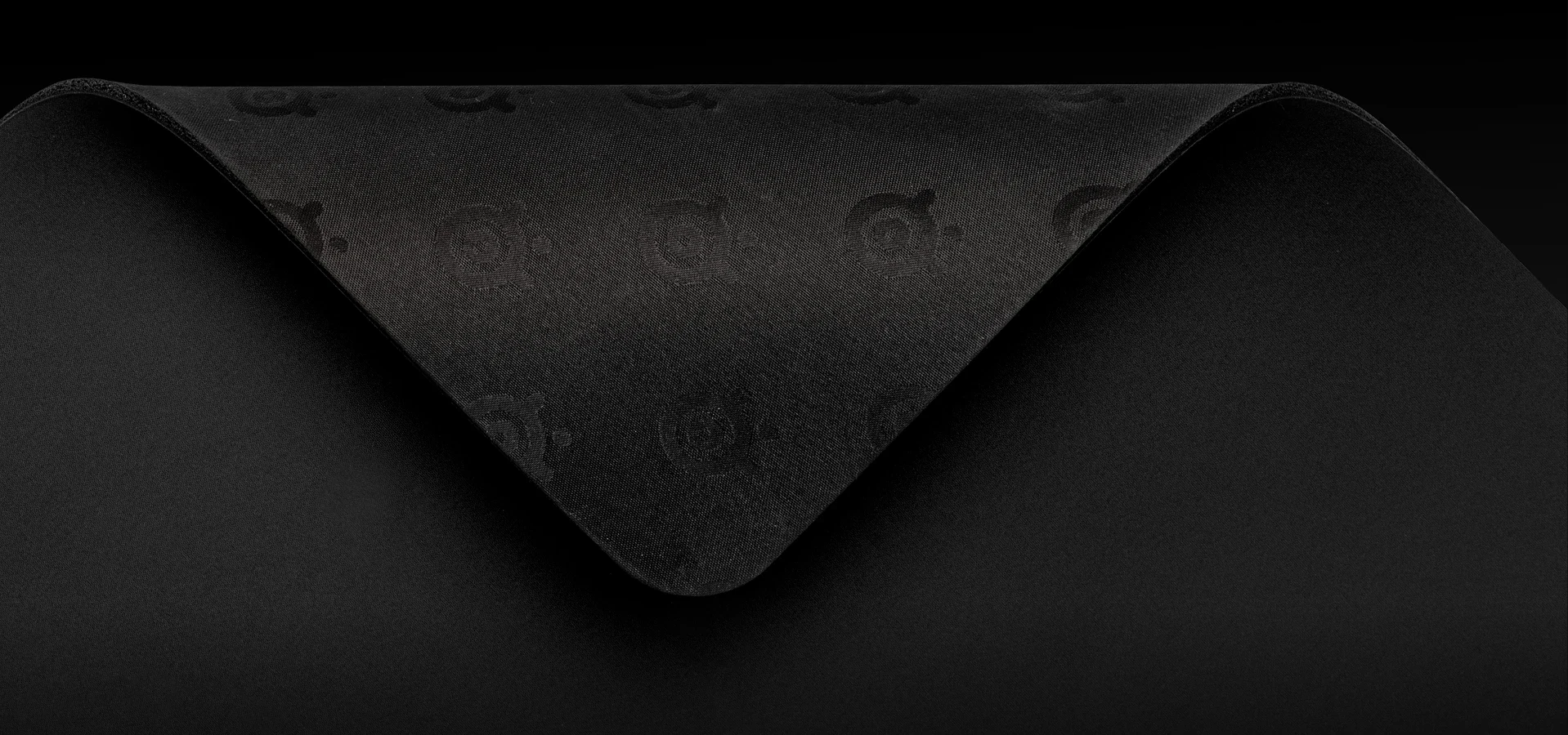 A close-up, top-down view of a black mousepad with embossed logos.